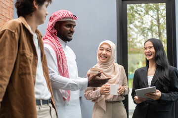 Fototapeta na wymiar Multicultural business team discussing project with digital tablet, arab businessman traditional attire collaborating with asian and caucasian colleagues, teamwork, business strategy, and technology