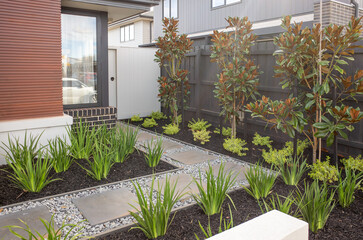 Neatly landscaped modern front yard in a suburban Australian home, featuring rectangular concrete...