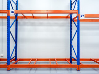 Empty red and blue metal warehouse rack, steel shelves with number panels sign, installed on bright...