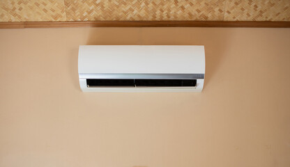 The air conditioner is installed inside the light yellow wall.