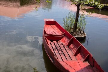 A red-painted rowboat floats on the water surface.