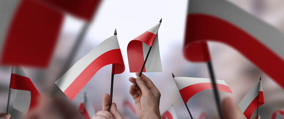 Poland flags in their hands on a blurred urban background