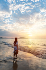 Young Asian woman traveler watching beautiful Sunset on the tranquil beach, Travel on summer vacation concept