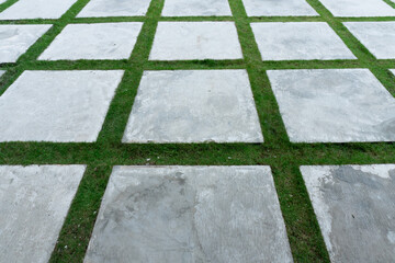 Geometric paving blocks with green grass in between, creating a modern and natural landscape design for outdoor paths, gardens, or minimalist courtyards.