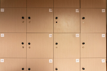 Row of wooden storage lockers with numbered labels, symmetrically aligned in a school, gym, or office setting.