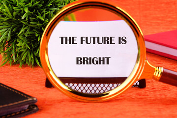 THE FUTURE IS BRIGHT concept words focuses through a magnifying glass on a business card on an...