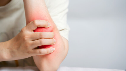 Woman experiencing elbow pain, clutching the inflamed area