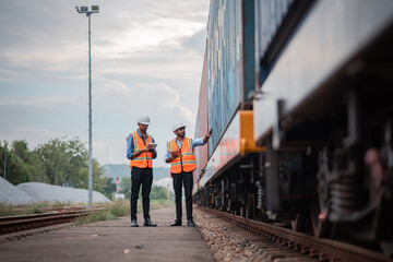 Engineers holding detail under survey and checking containers and industrial railway truck...