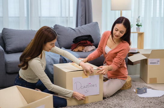 group of friend  sorting and packing clothes into a donation box.community support, and charitable giving
