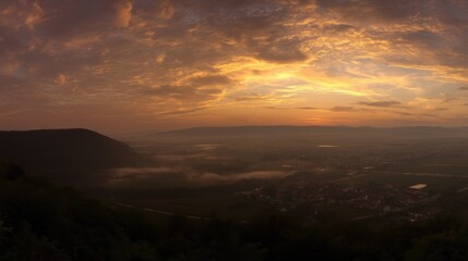 Obraz premium Golden sunset over a serene landscape, warm light through clouds, orange and purple hues blending in harmony