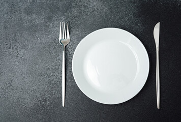 Plate and cutlery arranged on a dark surface ready for dining experience