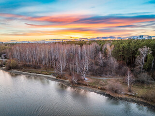 Colorful autumn forest with trees on the shore of a blue lake - top aerial view.