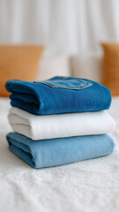 Neatly folded stack of jeans in blue and white colors on bed