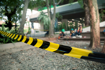 Striped black and yellow safety line stretched out around building renovation area with construction workers on the background