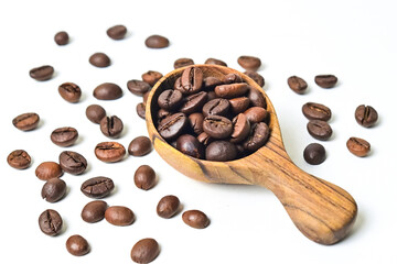 Close up view of roasted coffee beans in little wooden spoon. isolated on white background. Clipping path. Scattered. Cut out.