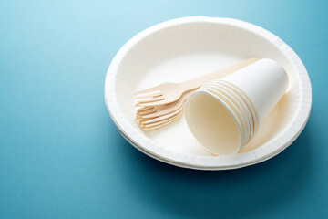 Closeup of white paper cups and wooden forks on eco-friendly plate