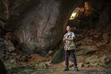 Tourist trekking with backpack and using a walking stick, gesturing forward suggesting of adventure or discovery in cave mysterious and ancient outdoor adventure concept.