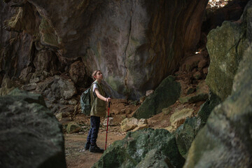 Tourist trekking with backpack and using a walking stick, gesturing forward suggesting of adventure or discovery in cave mysterious and ancient outdoor adventure concept.