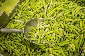 Frozen green beans on vegetable counter in freezer chest in supermarket close-up.