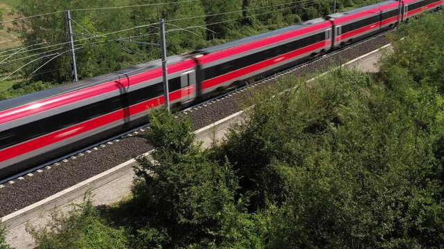 Aerial view of a train moving through trees and countryside, showcasing speed, travel, and innovation.