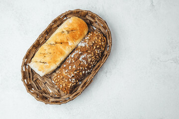 Freshly baked bread rolls in a woven basket on stone background
