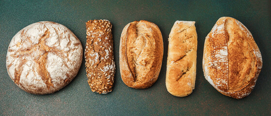 Variety of breads displayed on green surface in bakery setting