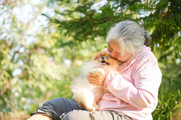 Asian Woman with Dog in Park, Senior Woman Relaxing with Pet Outdoors, Asian Woman and Pomeranian in Garden