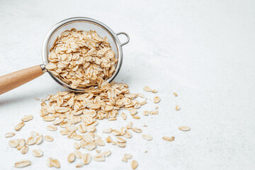 Oats spilling from a sieve onto a light surface during food preparation