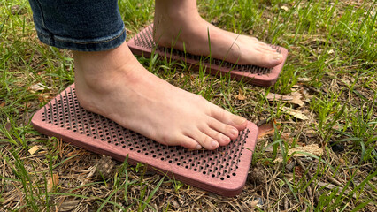 Barefoot acupressure on wooden spike massage boards outdoors – natural reflexology therapy for...