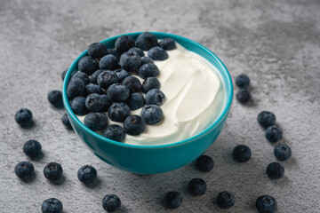 Top view of fresh blueberries on creamy yogurt in a blue bowl