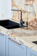 A modern kitchen sink has an elegant marble countertop and stylish faucet, enhancing its look