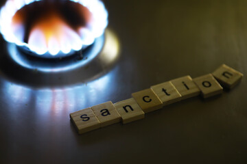 Sanction Concept with Wooden Tiles and a Burning Gas Stove in Background
