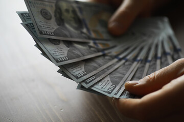 Hands Holding and Fanning Out Stack of One Hundred Dollar Bills