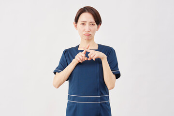 女性　美容看護師　指でバツのジェスチャー　白背景
