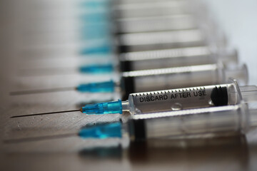 Row of Medical Syringes with Blue Needle Caps Highlighting Single-Use Instructions