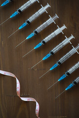 Medical Syringes with Measurement Tape on Wooden Surface - Health Care and Vaccination Concept