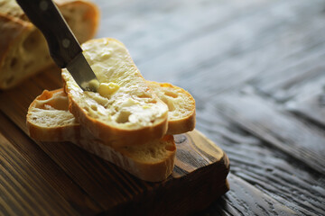 Spreading Butter on Freshly Sliced Rustic Bread on Wooden Cutting Board