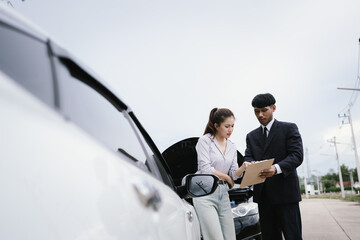 Man and woman standing by damaged car after accident, examining vehicle and filing insurance claim...