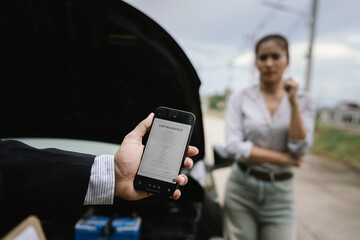 Man inspecting damaged car after crash, documenting insurance claim with mobile phone, showing frustration, analysis, and need for repair service.