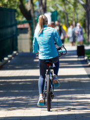 A woman is riding a bicycle down a sidewalk