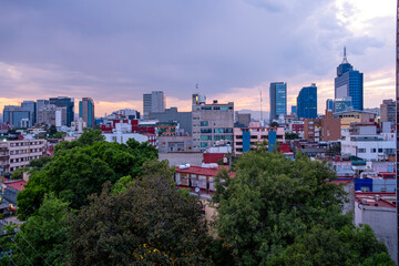 Mexico City skyline with green trees, colorful facades, and tall buildings, elevated view ideal for real estate, business, and architecture stock applications.