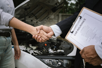 Man inspecting damaged car after crash, documenting insurance claim with mobile phone, showing frustration, analysis, and need for repair service.