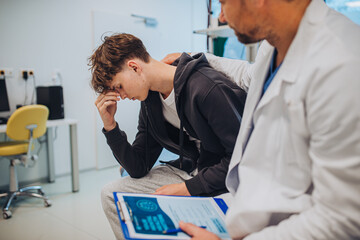 Close-up of doctor and teenage patient filling out mental health evaluation form.