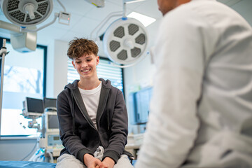 Teenage boy smiling during medical consultation after receiving positive health news.