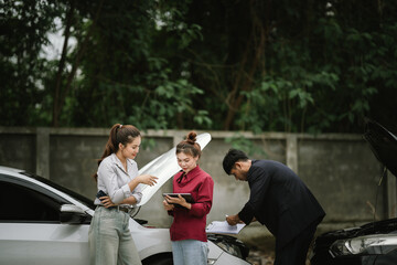 Man inspecting damaged car after crash, documenting insurance claim with mobile phone, showing...
