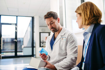 Female medical sales representative introducing pharmaceutical products to doctor.