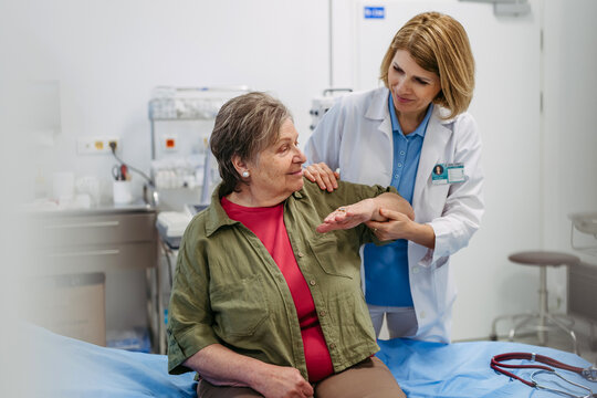 Geriatrician examining senior woman's mobility during routine check-up,