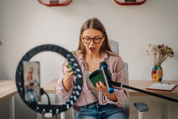 Influencer woman is unboxing small products while recording video blog