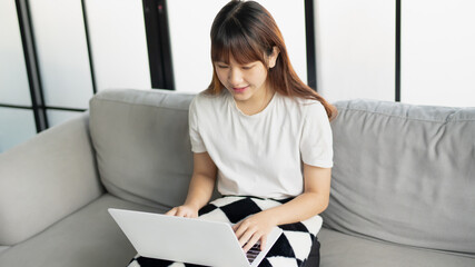 Asian woman in casual sitting using laptop
