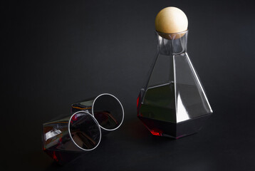 Tinted glass decanter and two tumblers arranged on a dark background, ideal for showcasing wine service in bar menus, party invites, or interior design editorials. Photo